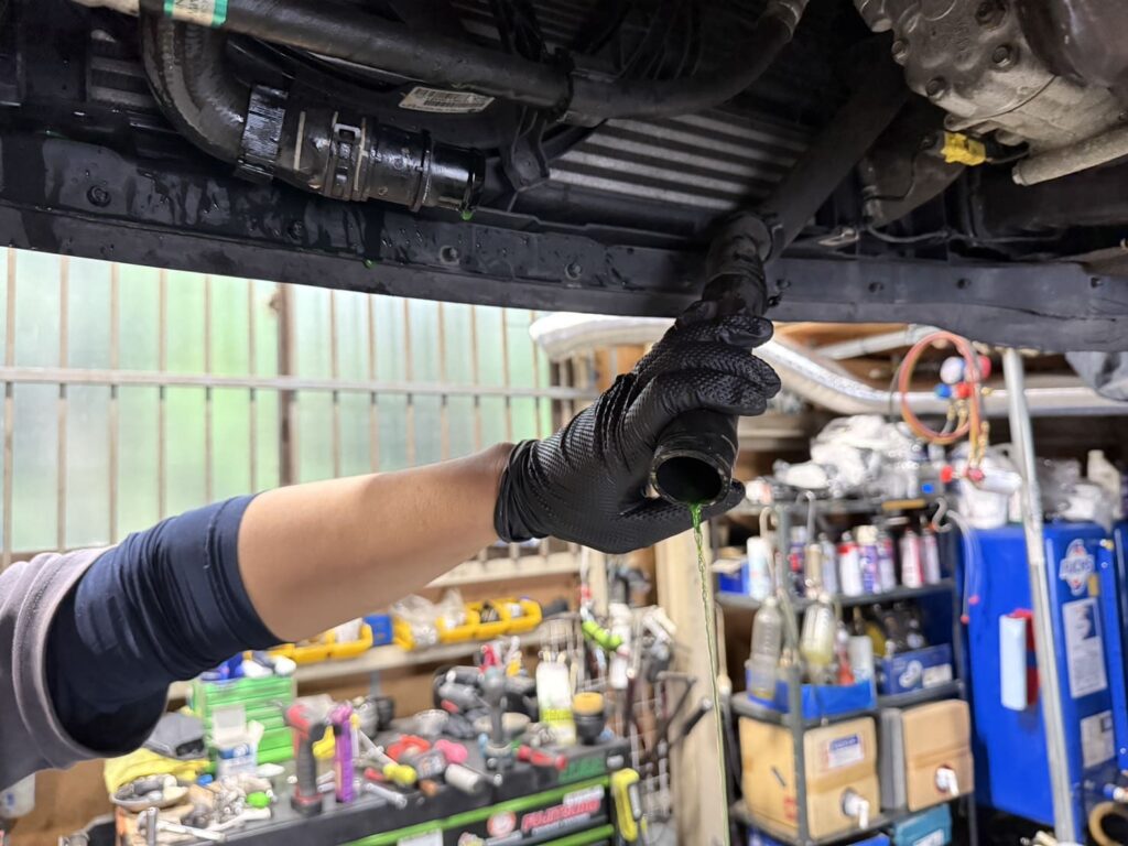 オイルフィルターハウジングガスケット交換前ににクーラントを抜いている様子